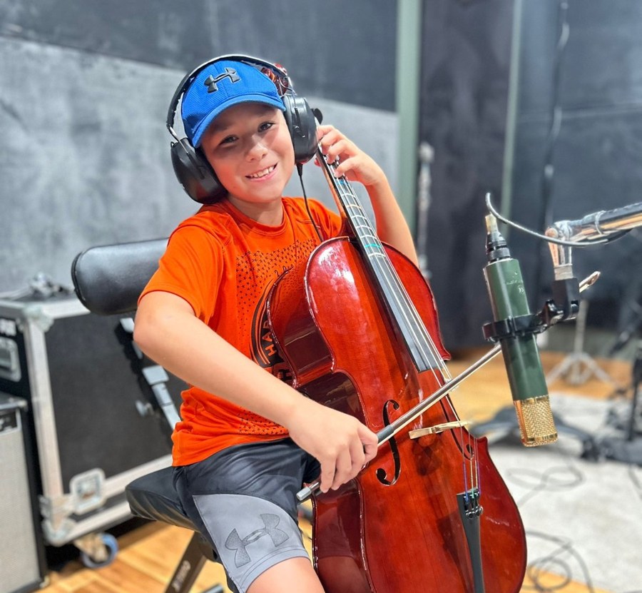 A young cellist smiling during an IME studio recording